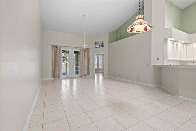 tiled empty room featuring ceiling fan, french doors, and a towering ceiling