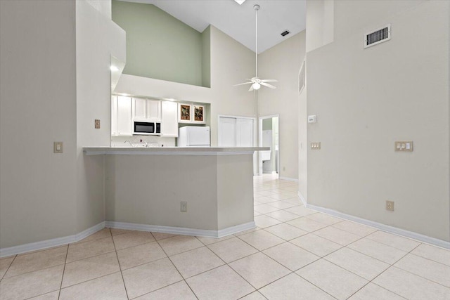 kitchen featuring white cabinetry, white appliances, ceiling fan, kitchen peninsula, and a high ceiling