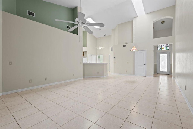 unfurnished living room with a high ceiling, ceiling fan, and light tile patterned floors