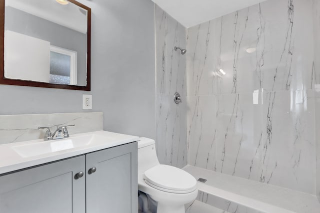 bathroom featuring a tile shower, vanity, and toilet