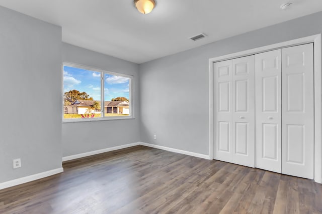 unfurnished bedroom featuring a closet and dark hardwood / wood-style floors