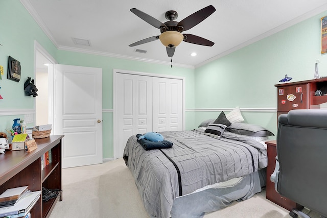 carpeted bedroom with ceiling fan, a closet, and ornamental molding