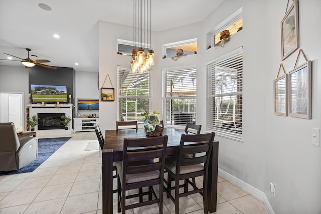 dining room with ceiling fan with notable chandelier, a large fireplace, and light tile patterned floors