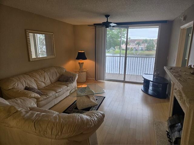 living room featuring a textured ceiling, ceiling fan, and light hardwood / wood-style flooring