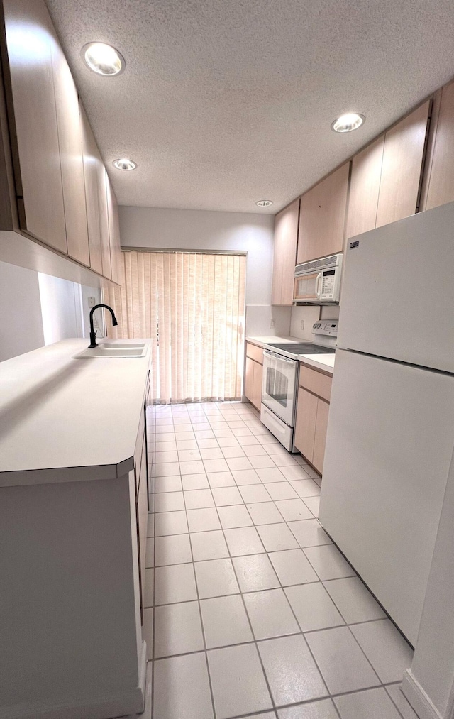 kitchen featuring sink, light tile patterned floors, white appliances, light brown cabinets, and a textured ceiling