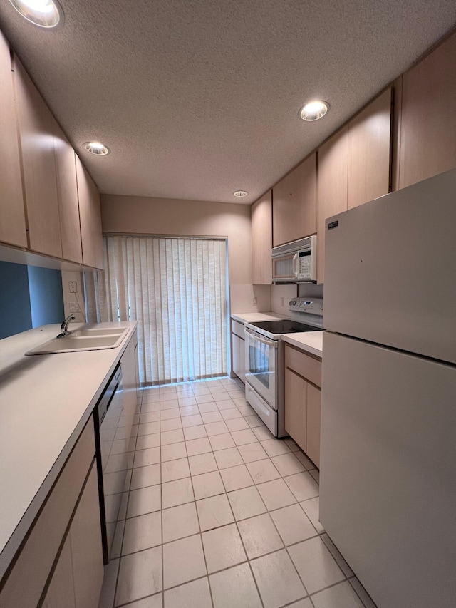 kitchen featuring a textured ceiling, light tile patterned floors, sink, and white appliances