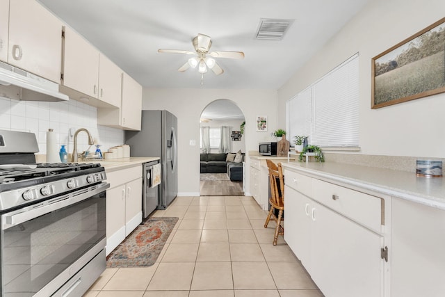 kitchen featuring ceiling fan, tasteful backsplash, light tile patterned floors, stainless steel appliances, and white cabinets