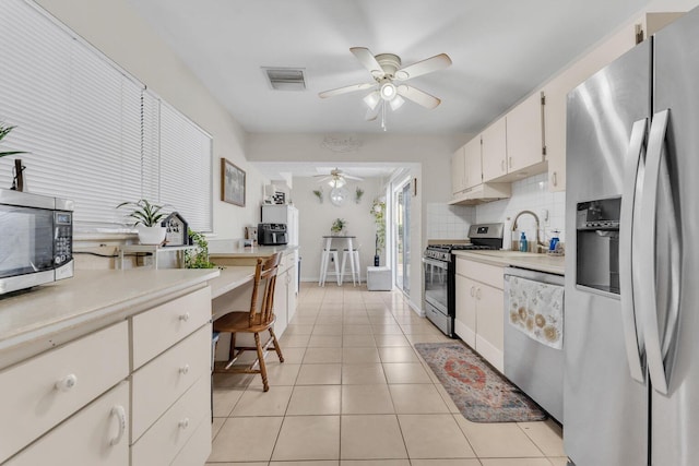 kitchen with ceiling fan, decorative backsplash, light tile patterned floors, appliances with stainless steel finishes, and white cabinets