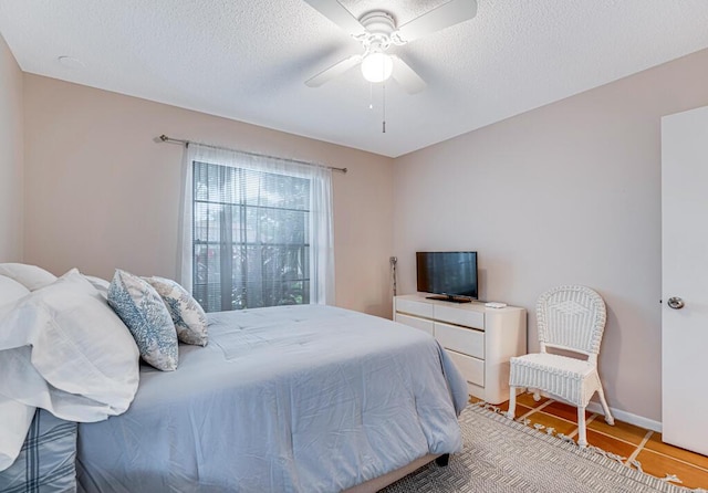 tiled bedroom with ceiling fan and a textured ceiling