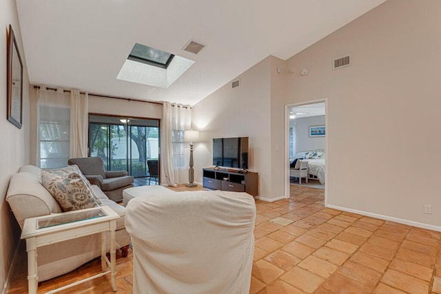 living room featuring ceiling fan, light tile patterned floors, and lofted ceiling with skylight