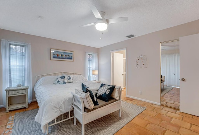 bedroom with a textured ceiling, ceiling fan, and light tile patterned floors