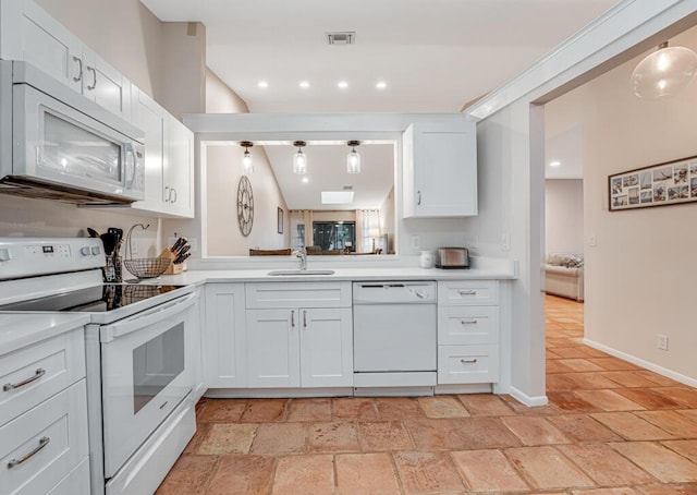 kitchen with hanging light fixtures, white cabinets, sink, and white appliances