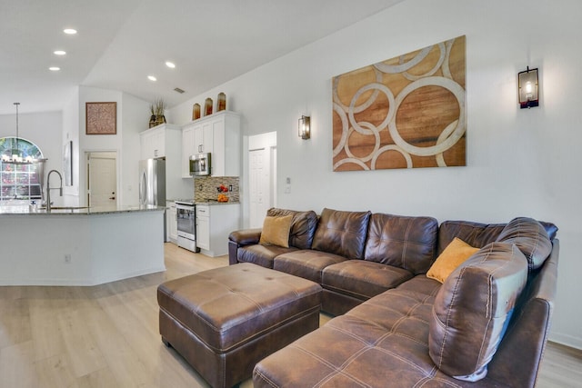 living area with light wood finished floors, visible vents, lofted ceiling, a chandelier, and recessed lighting