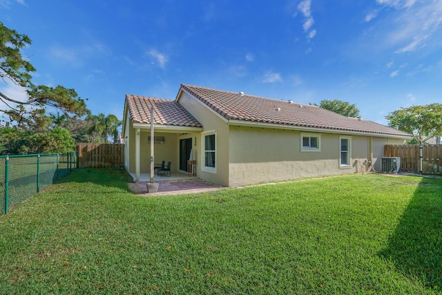 back of property featuring a lawn, a fenced backyard, a tiled roof, cooling unit, and stucco siding