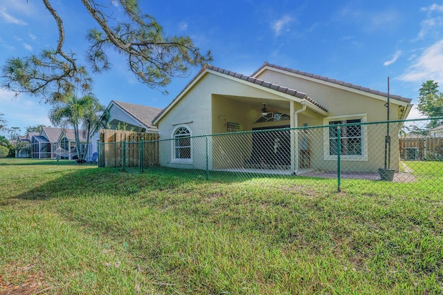 exterior space featuring ceiling fan, fence, a lawn, and stucco siding