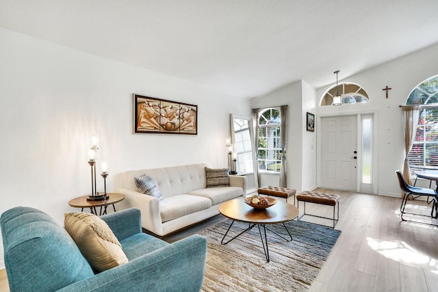 living area featuring vaulted ceiling, baseboards, and light wood-style floors