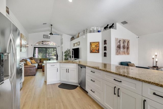 kitchen featuring stainless steel appliances, vaulted ceiling, white cabinetry, and open floor plan