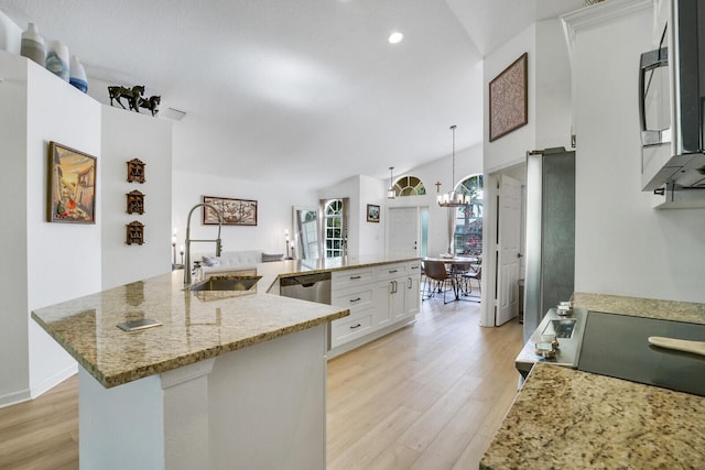 kitchen with appliances with stainless steel finishes, a large island with sink, white cabinets, and hanging light fixtures