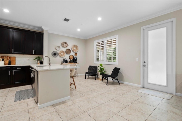 kitchen featuring crown molding, a breakfast bar, sink, and light tile patterned floors