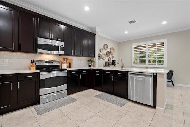 kitchen with sink, light tile patterned floors, crown molding, appliances with stainless steel finishes, and kitchen peninsula