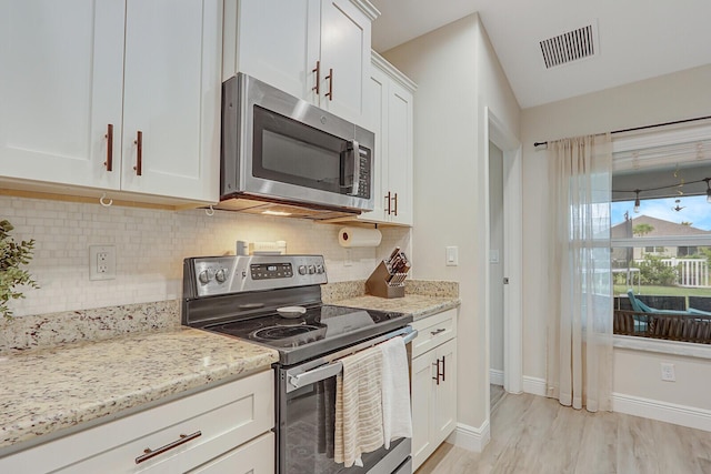 kitchen featuring light stone countertops, white cabinets, decorative backsplash, and appliances with stainless steel finishes