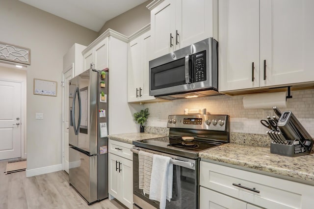 kitchen featuring light stone countertops, decorative backsplash, light wood-type flooring, white cabinetry, and appliances with stainless steel finishes