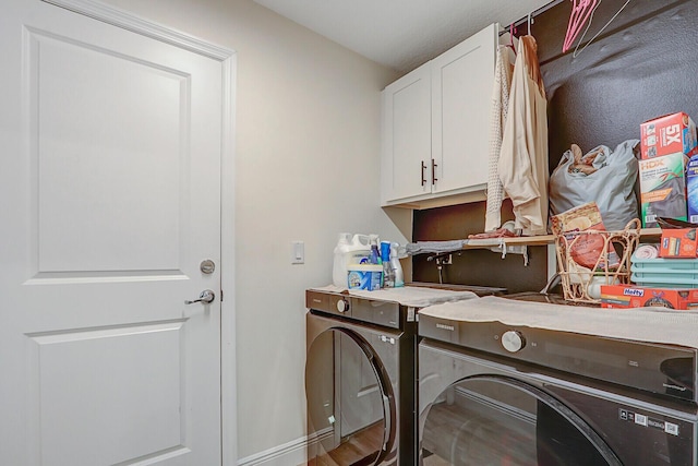 clothes washing area with washer and dryer, cabinets, and hardwood / wood-style flooring