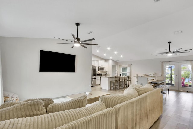 living room featuring vaulted ceiling, light wood-type flooring, and french doors