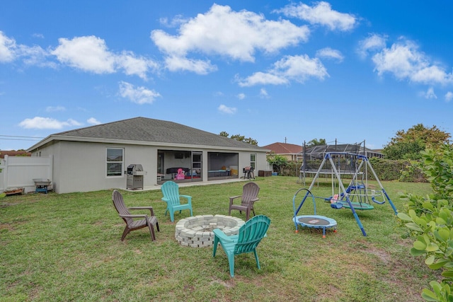 view of yard featuring an outdoor fire pit, a playground, and a trampoline