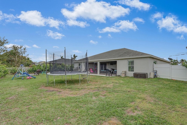 back of property featuring a yard, a playground, and a trampoline