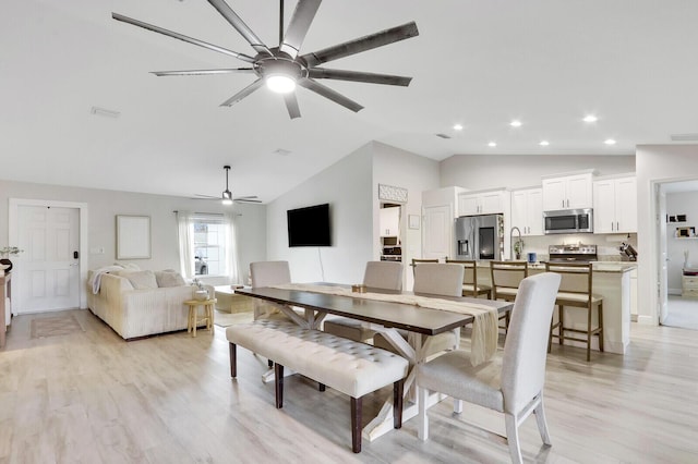 dining space featuring ceiling fan, vaulted ceiling, and light hardwood / wood-style flooring