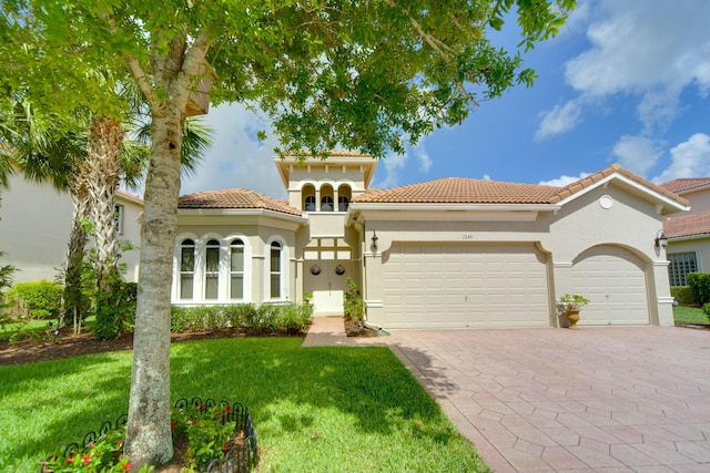 mediterranean / spanish home featuring a garage and a front lawn