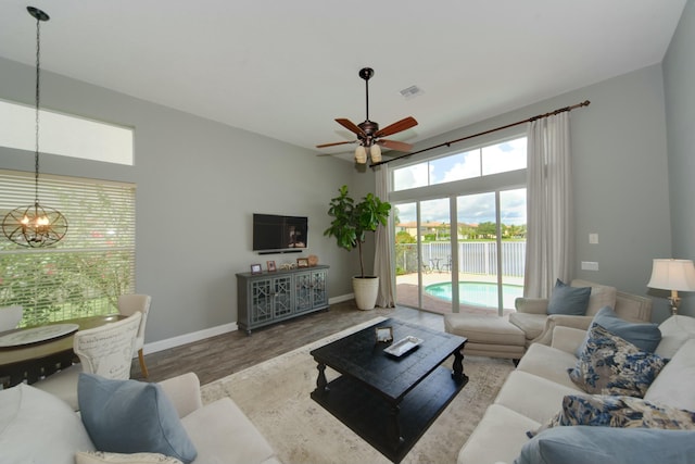 living room with wood-type flooring and ceiling fan with notable chandelier