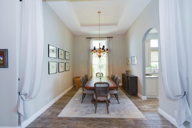 dining area with hardwood / wood-style flooring, sink, a raised ceiling, and a chandelier