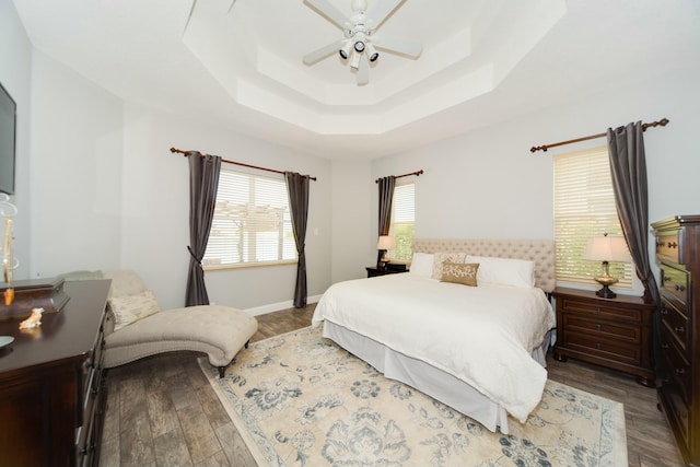 bedroom with a raised ceiling, hardwood / wood-style flooring, and ceiling fan