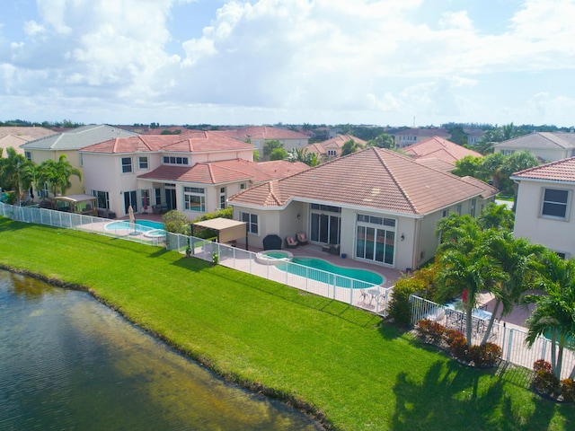 back of house with a water view and a lawn