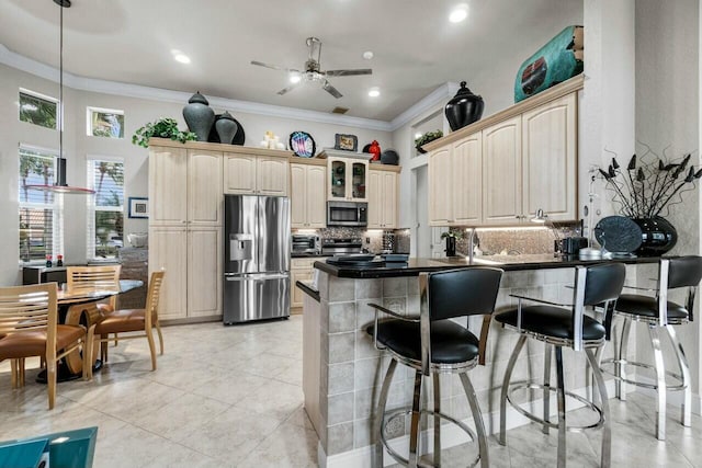 kitchen featuring backsplash, kitchen peninsula, a kitchen bar, crown molding, and stainless steel appliances