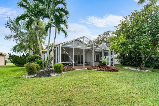 rear view of property featuring glass enclosure and a lawn