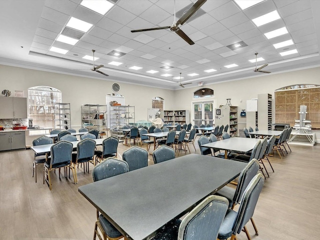 dining space with ceiling fan, a drop ceiling, and light wood-type flooring