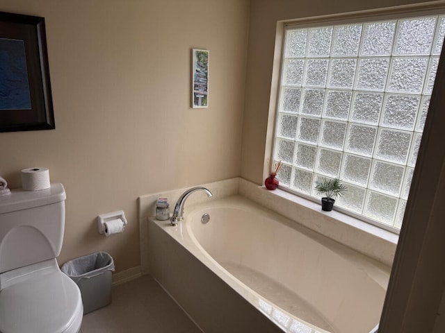 bathroom featuring a tub, toilet, and a healthy amount of sunlight