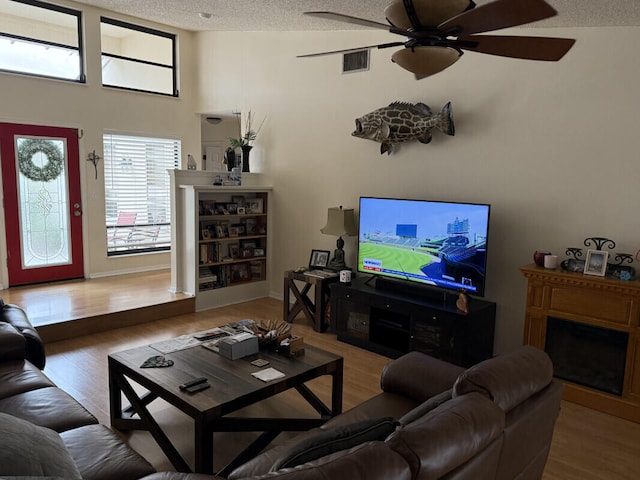 living room with ceiling fan, wood-type flooring, and a textured ceiling