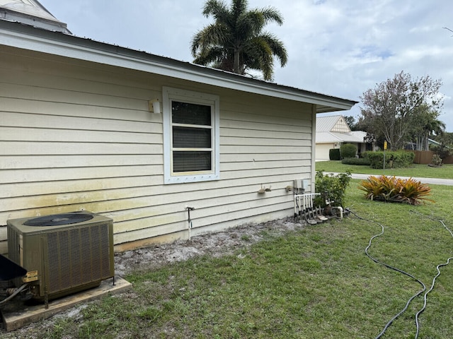 view of side of home with central AC unit and a lawn