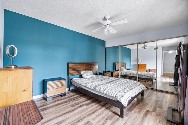 bedroom featuring hardwood / wood-style flooring, a closet, ceiling fan, and a textured ceiling