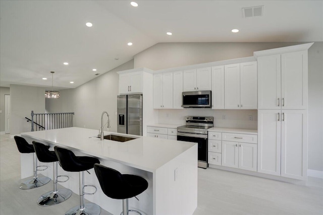 kitchen featuring white cabinets, appliances with stainless steel finishes, sink, hanging light fixtures, and a kitchen island with sink