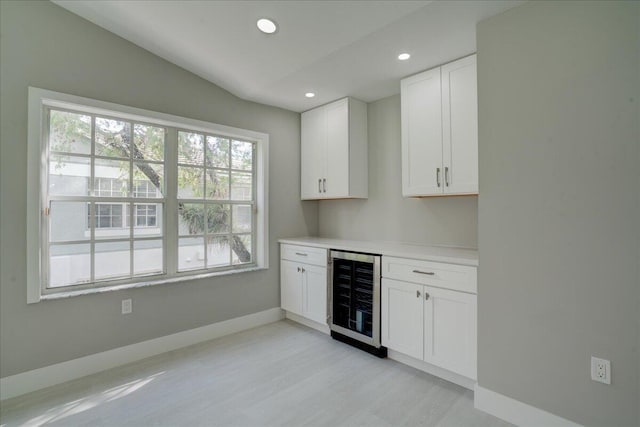 bar featuring white cabinetry, beverage cooler, and lofted ceiling