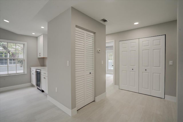 corridor with light hardwood / wood-style floors and beverage cooler