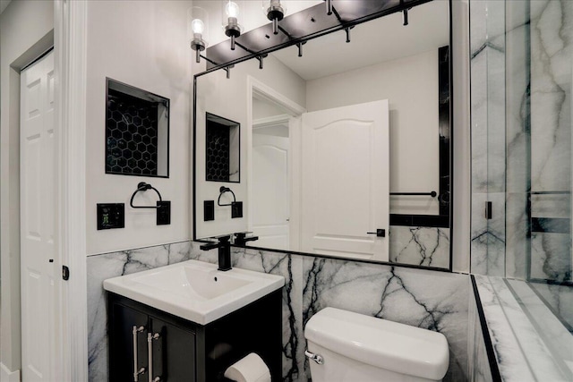 bathroom with tile walls, toilet, and vanity