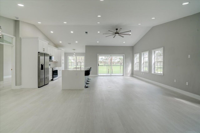 kitchen featuring appliances with stainless steel finishes, white cabinetry, an island with sink, sink, and a breakfast bar