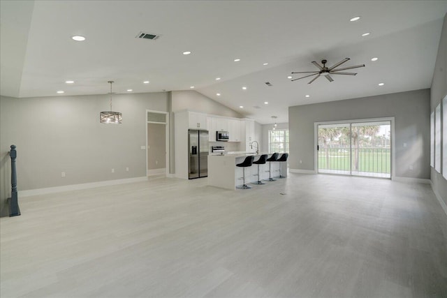 unfurnished living room with sink, light wood-type flooring, and high vaulted ceiling