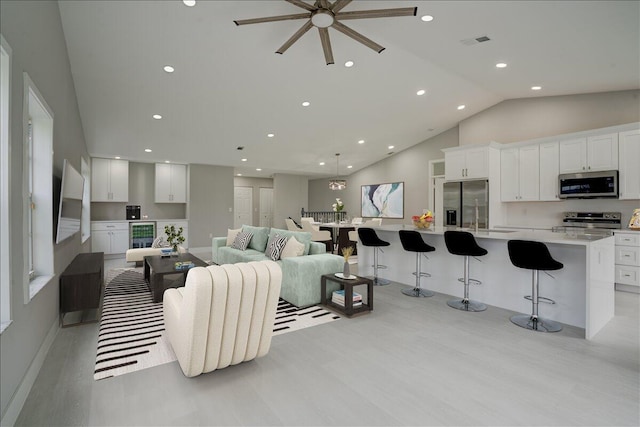 living room with light hardwood / wood-style floors, lofted ceiling, and wine cooler